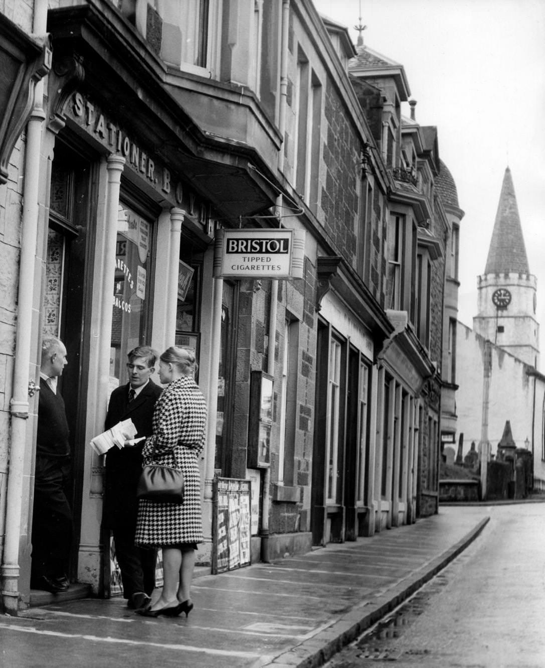 #138 Candidate Andrew Forrester and his wife chat with a shopkeeper in Comrie, Scotland, 1963