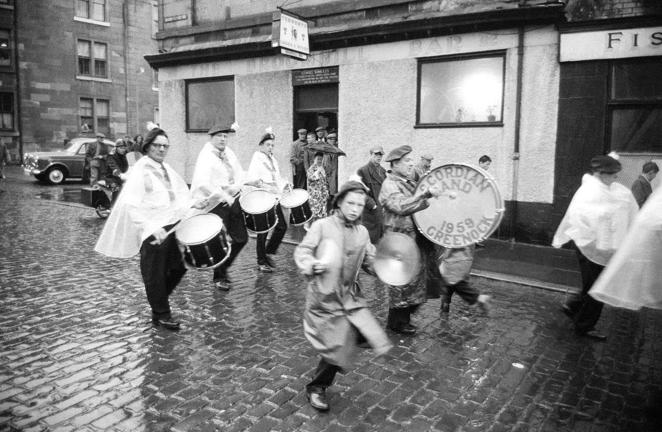 #45 Drummers of the Greenock Accordian Band marching in the rain, Greenock, Scotland, 1963.