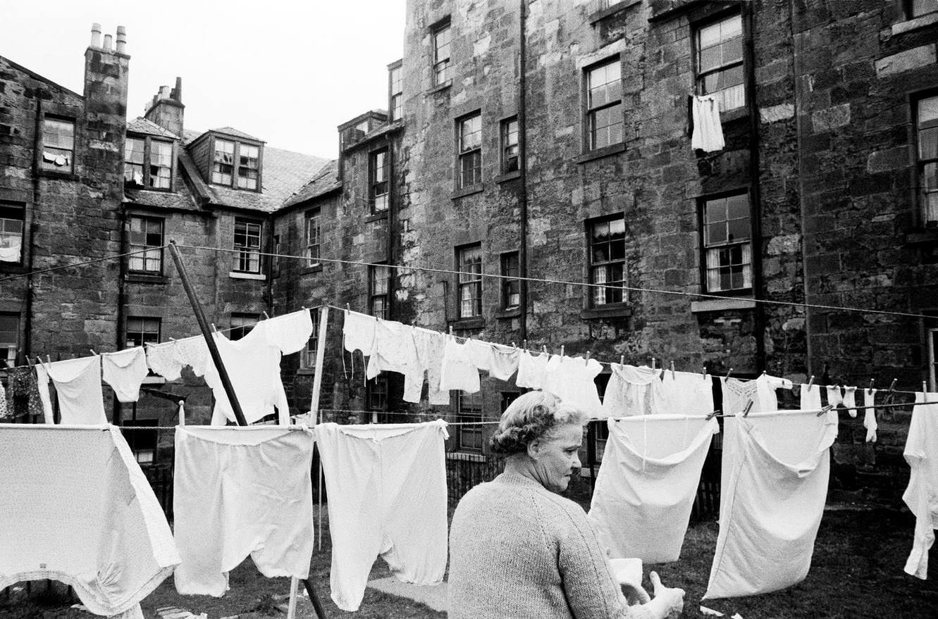 #48 A woman hangs out her laundry on a washing line between tenements in Greenock, Renfrewshire, Scotland, 1963.
