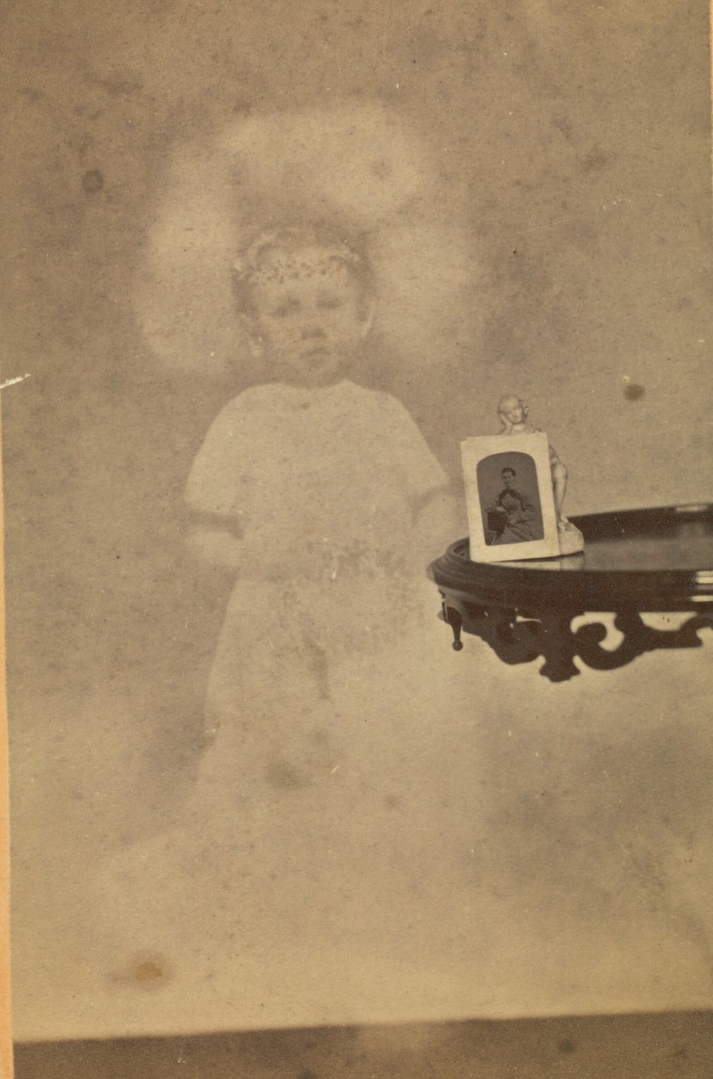 #11 Small statuette and photograph on a side table, with the faint image of a young boy floating next to it.