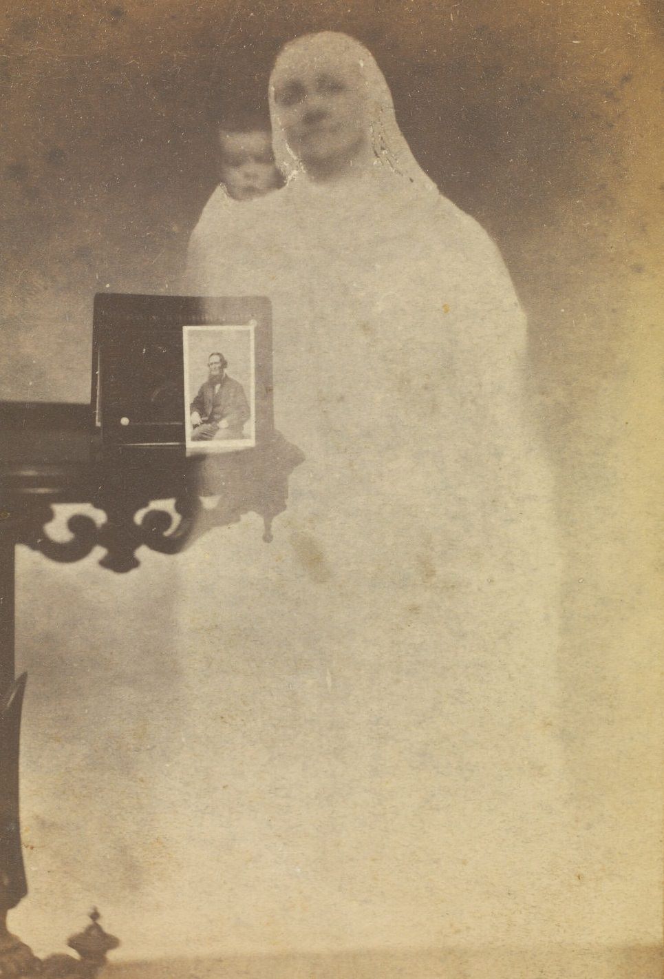 #14 A portrait of Mr. Tinkham perched on a side table, with the faint image of a woman and baby next to it.