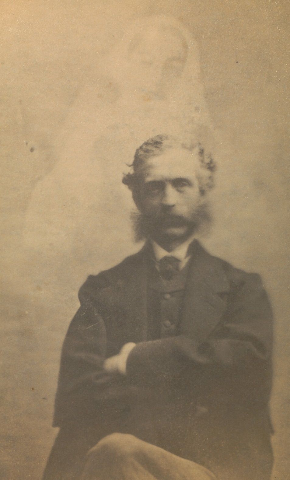 #17 Portrait of a seated man, facing the camera with his arms folded across his chest.