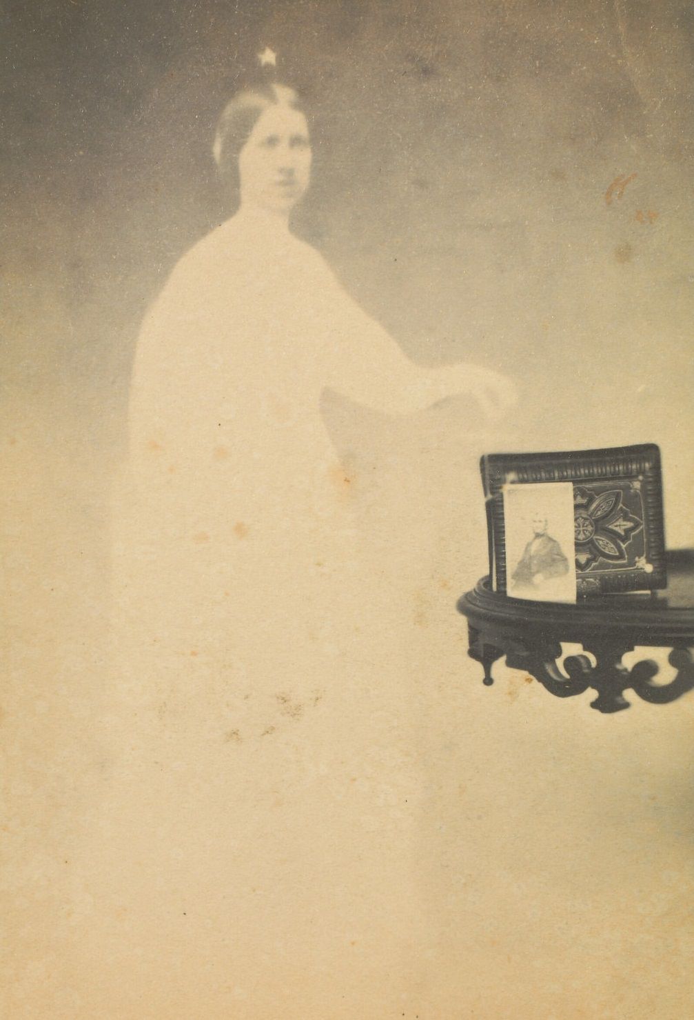 #19 A photograph propped against an album on a side table, with the faint image of a woman next to it.