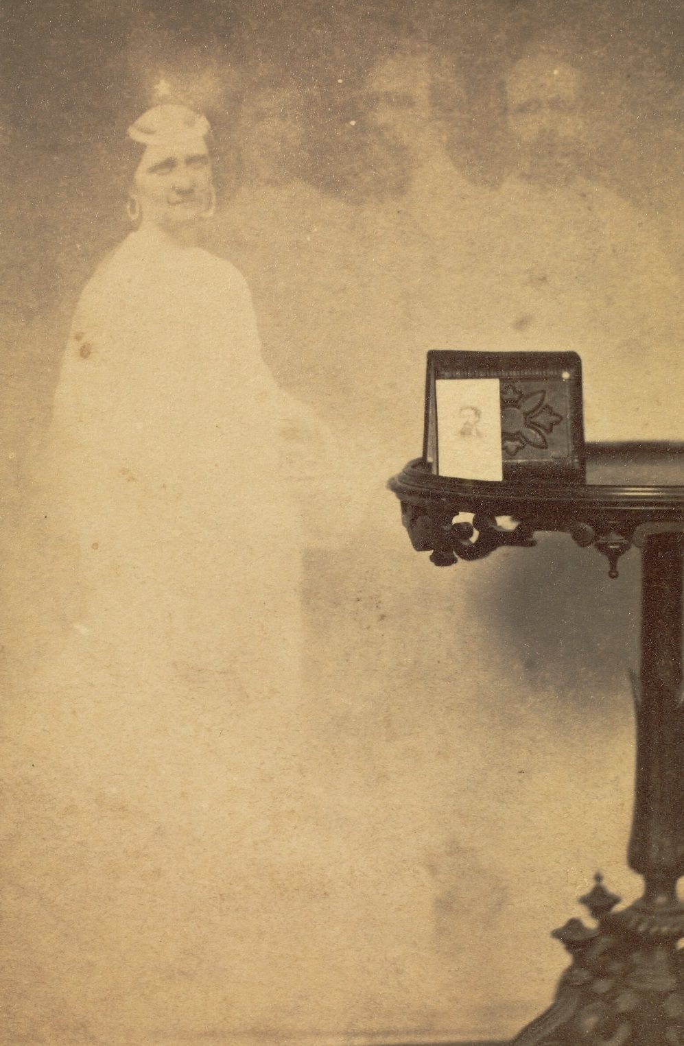 #34 A photograph propped against an album on a side table, with faint images of a woman and three men floating next to the table.