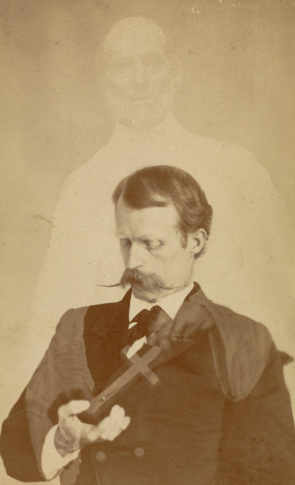 #36 Portrait of Harry Gordon looking down into his hand, while the faint figure of a bearded man appears behind him, with hands that seem to be placing a crucifix into the open hand of the sitter.