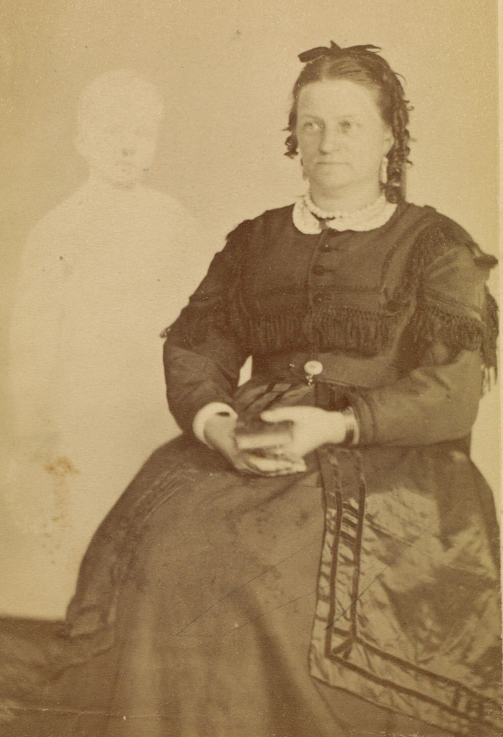 #7 Portrait of Mrs. French, wearing a dark dress, holding a book in her lap. The faint image of a boy appears beside her.