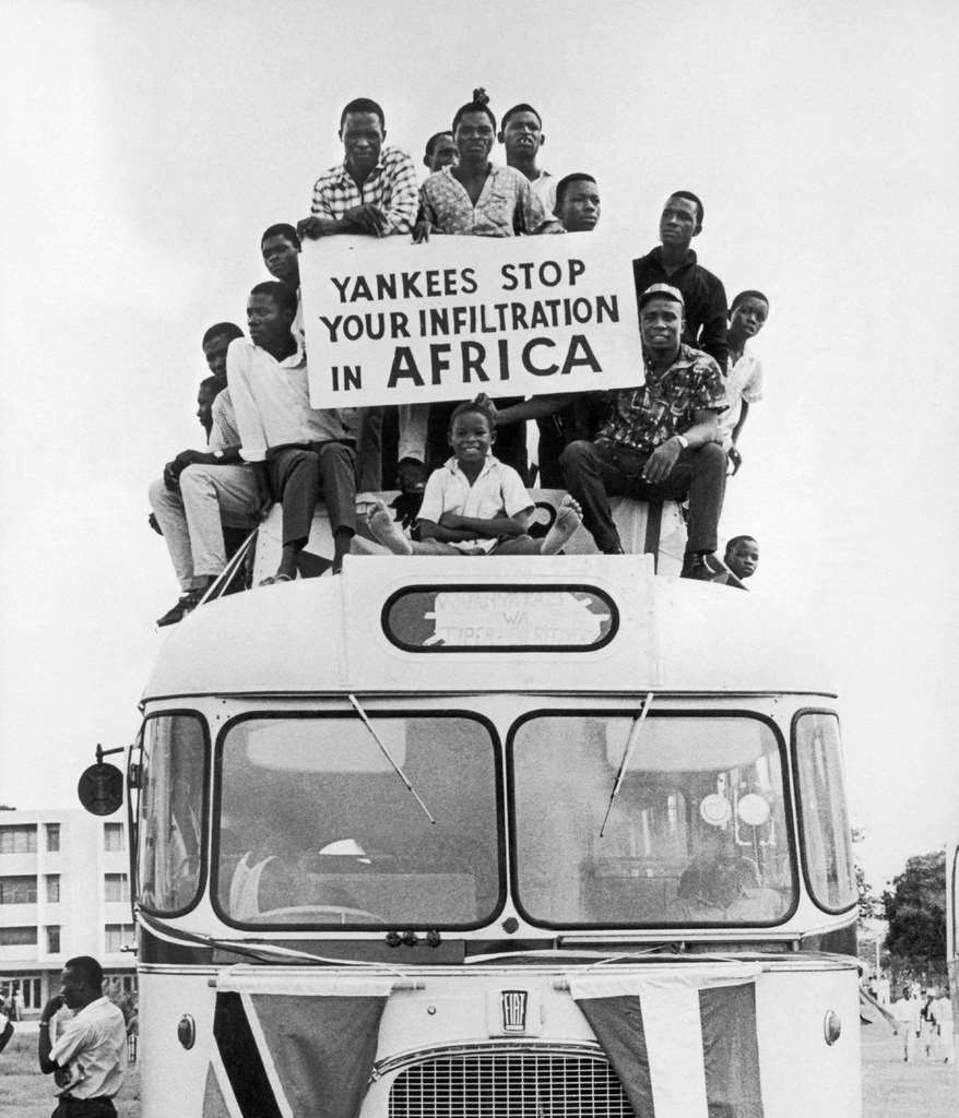 #31 On the roof of a bus, Tanzanians protest against US imperialism with a banner that reads ‘Yankees, stop infiltrating Africa’, in Tanzania, August 4, 1967.