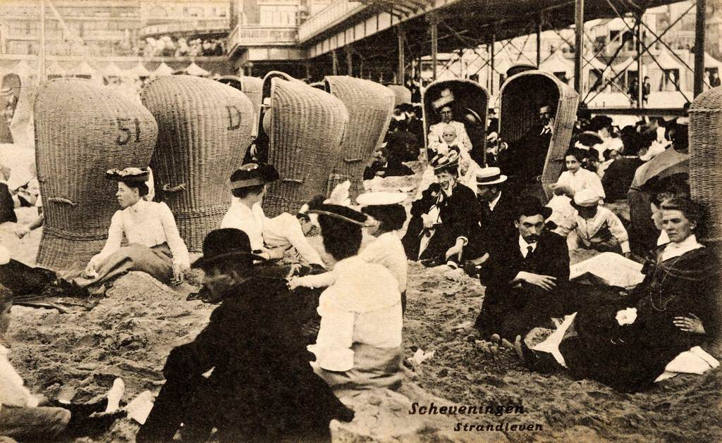 #36 Holidaymakers sitting on the sand and in beach chairs at the seaside in Scheveningen near The Hague in the Netherlands, 1908.