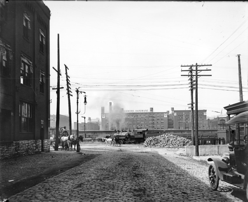 #134 A cobblestone cross-street fitted with a gas powered street light and a series of telephone wires, 1908