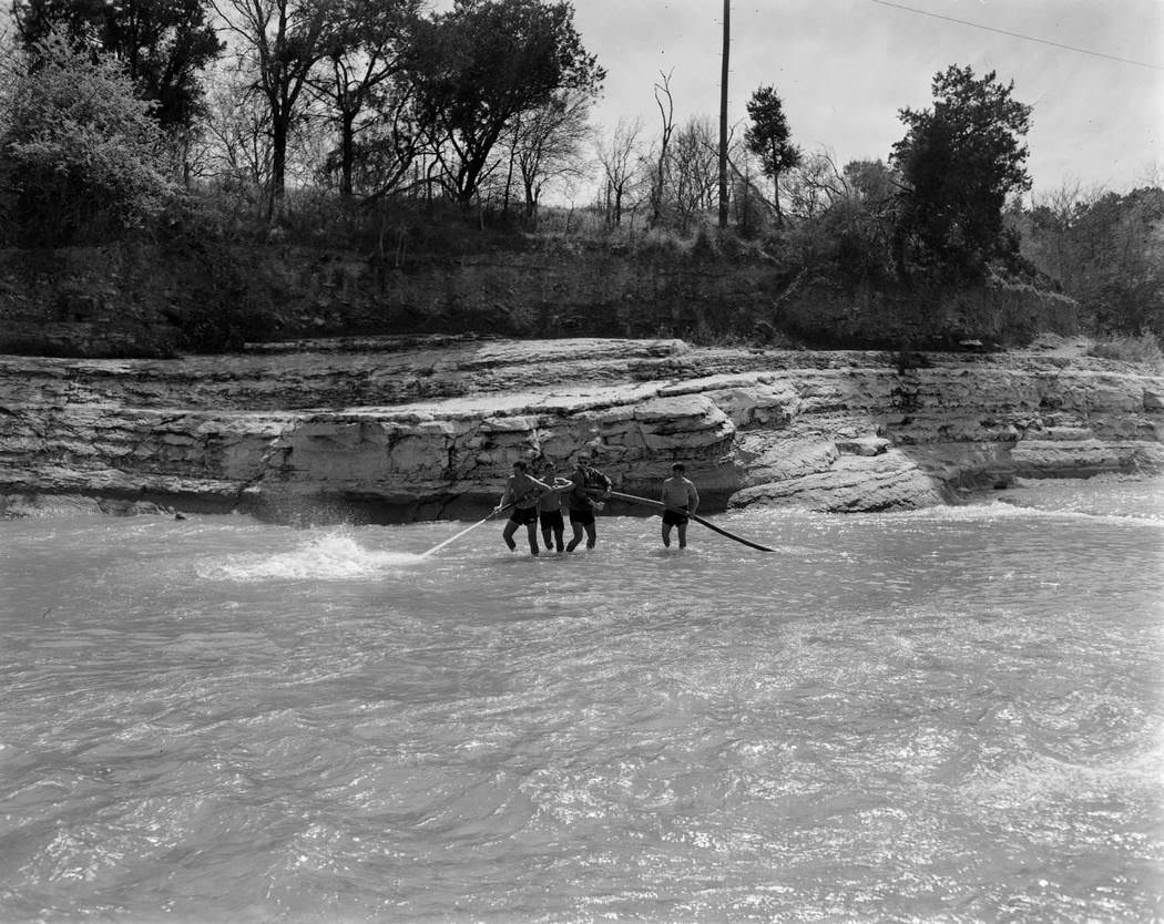 #6 A group of people holding a hose in the middle of Barton Pool, 1970