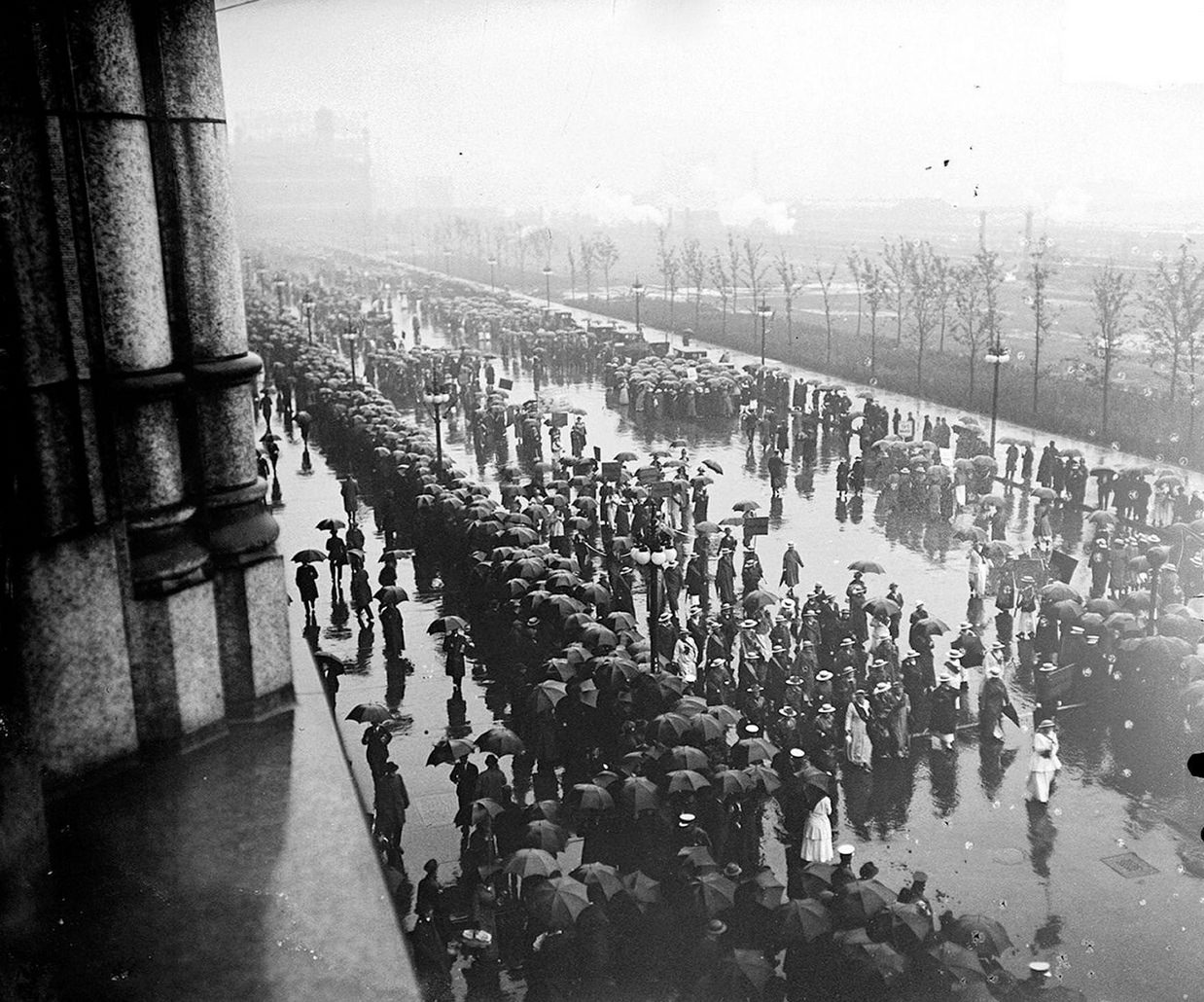 #36 The suffrage parade, with spectators looking on in the rain, on South Michigan Avenue across from Grant Park in the Loop community area of Chicago, Illinois, 1910s.
