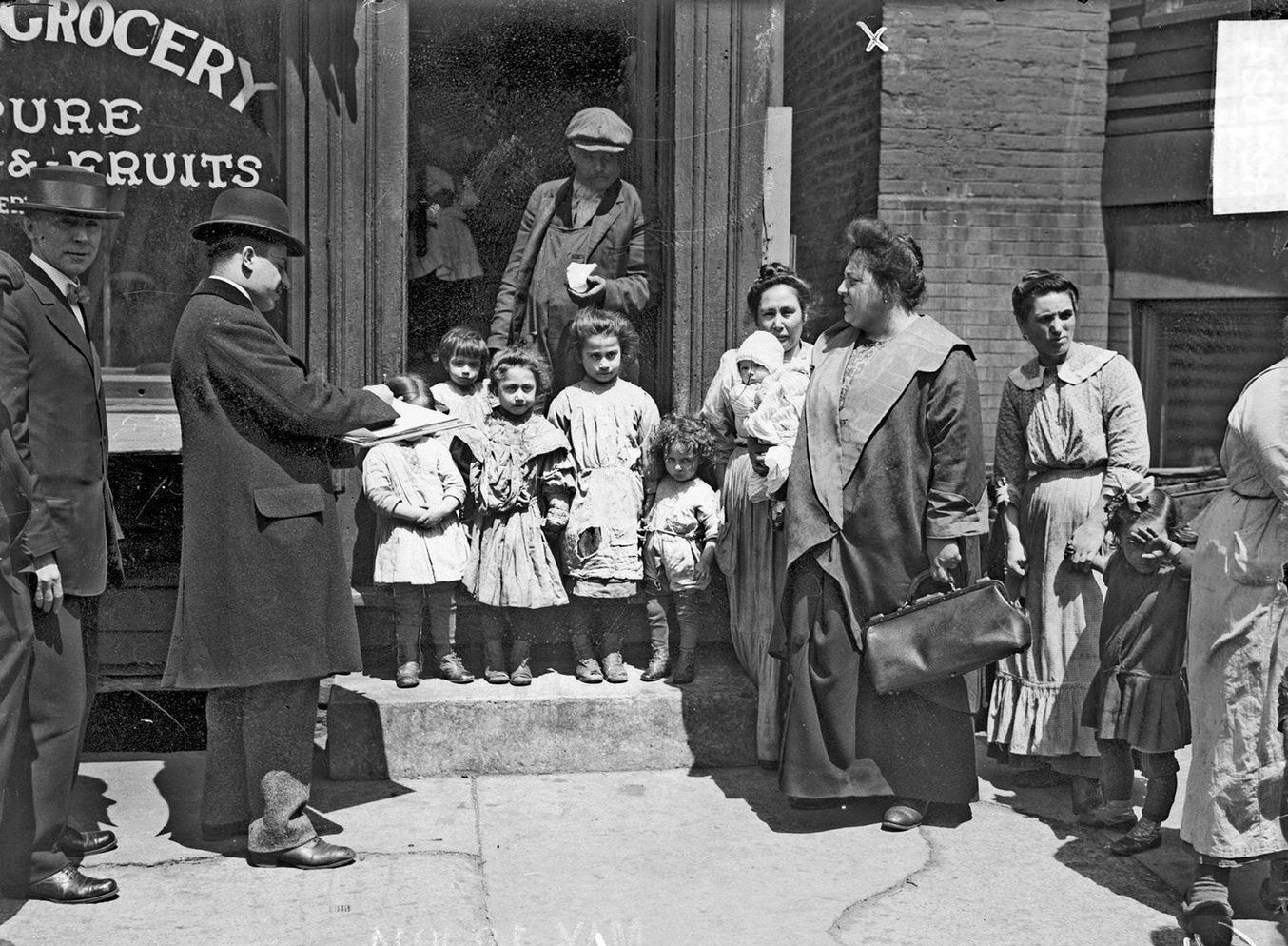 #12 Annie Carlo-Blasi, queen of Little Italy, standing beside grocery store with men, women, and children, Chicago, Illinois, 1914.