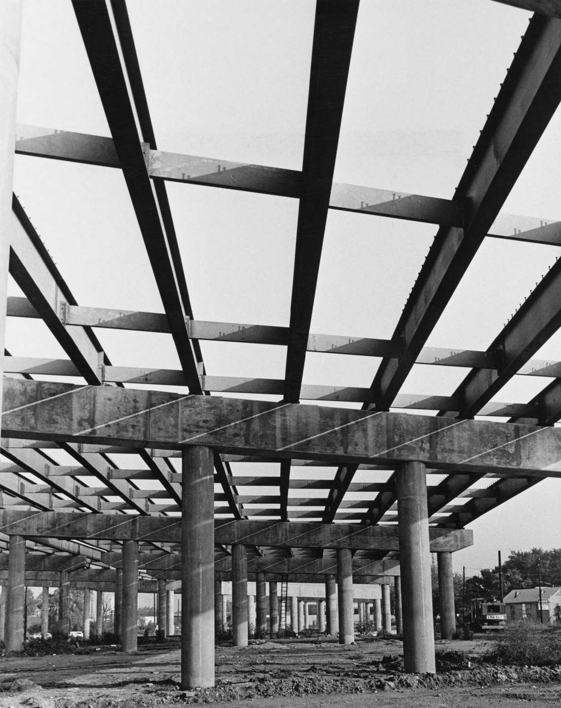#246 View up through the uncompleted steel framework of a bridge or road flyover, raised on reinforced concrete pillars, under construction in Dallas, Texas, 1955.