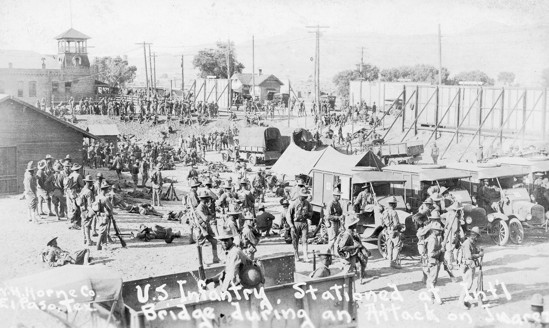 #1 Group shot of many African American members of the United States Infantry, outside and among tents, buildings, and equipment, at the International Bridge in El Paso, 1900s