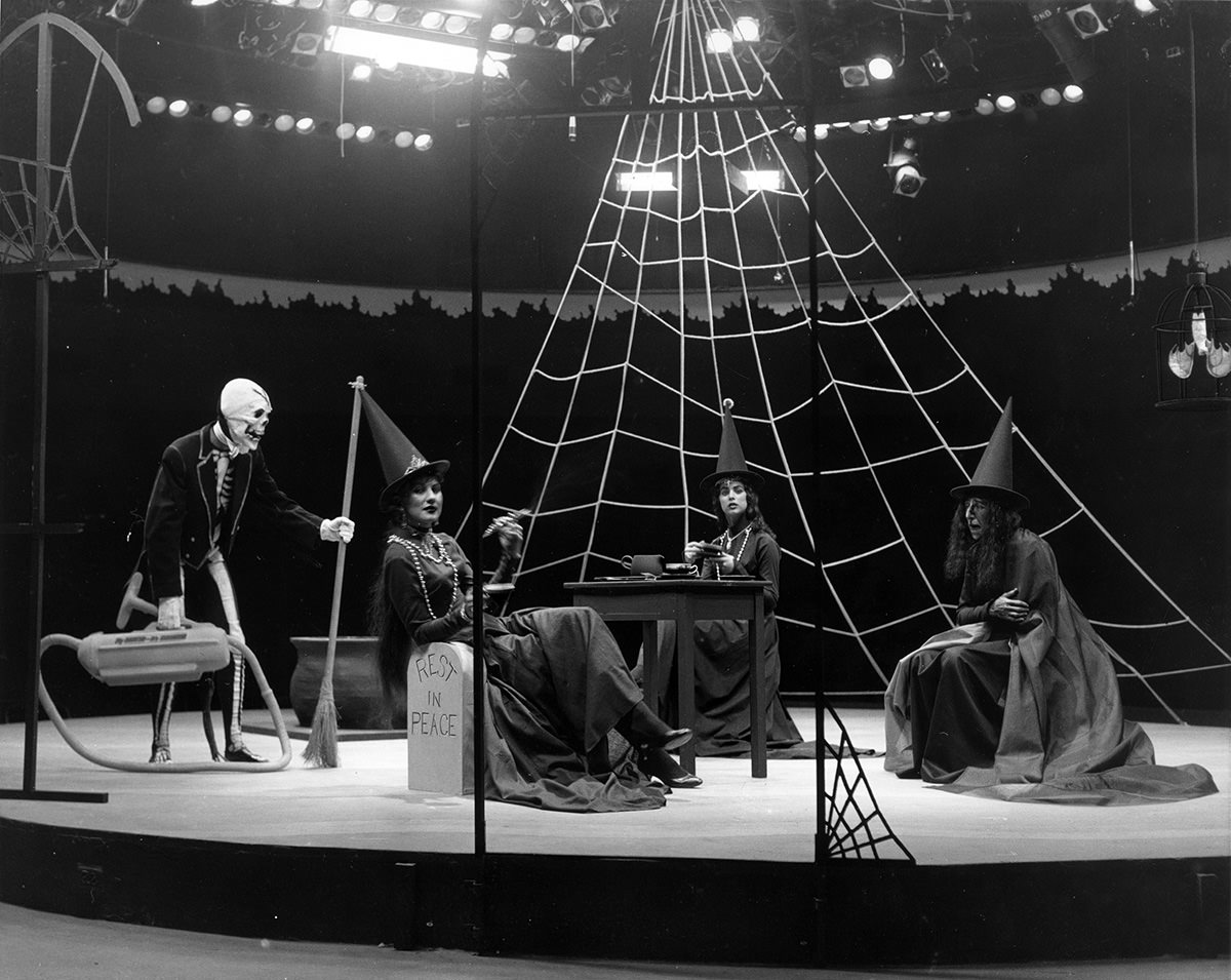 #115 Casa Manana – Three women dressed as witches lounging on stage, a skeleton butler with broom and vacuum in “Wizard of Oz,” 1961.