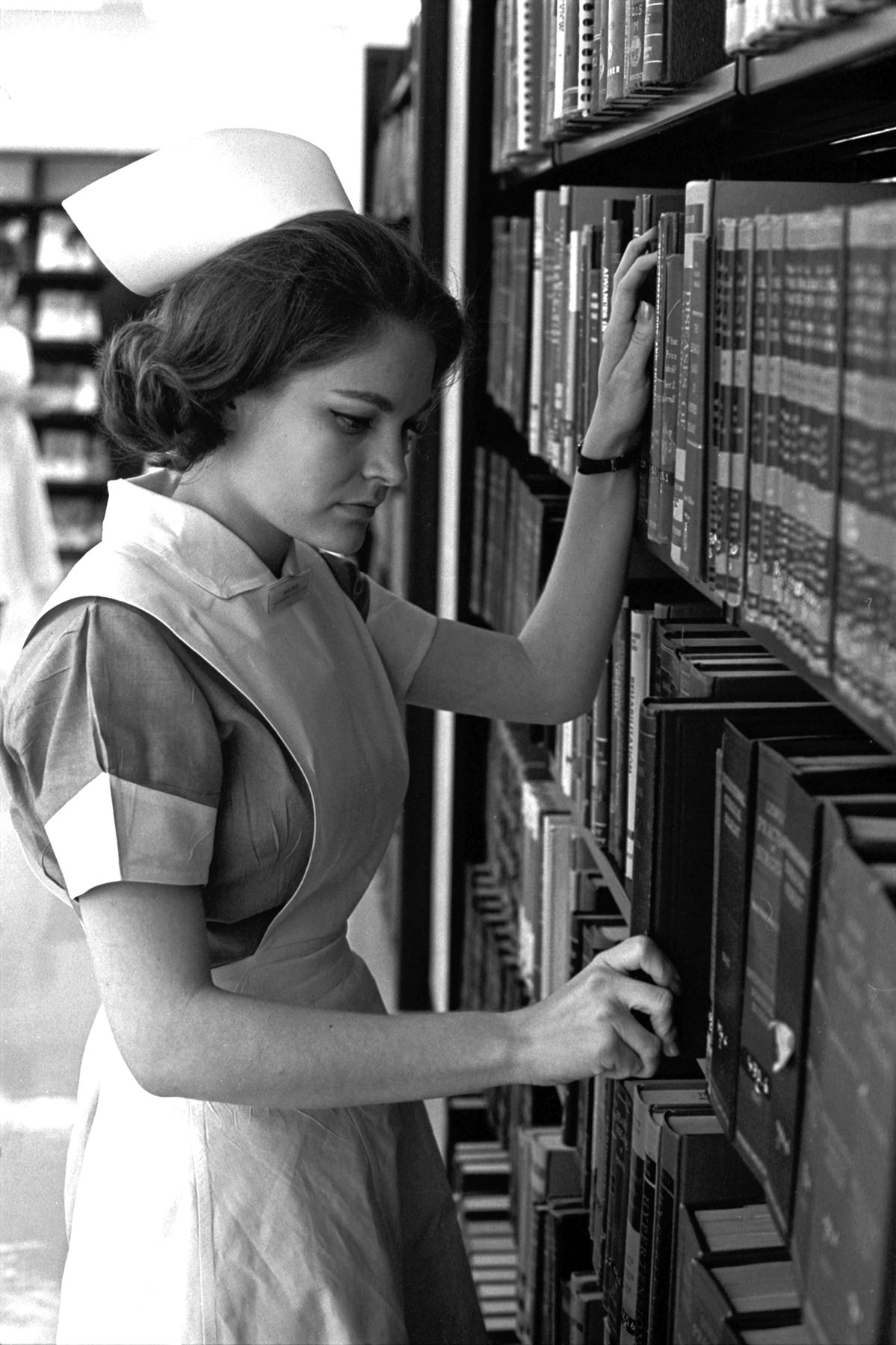 #116 Miss Alita Rose, president of one of the two classes of student nurses at John Peter Smith Hospital School of Nursing, locates a book in the library and prepares to spend a couple of hours in quiet study, 1965