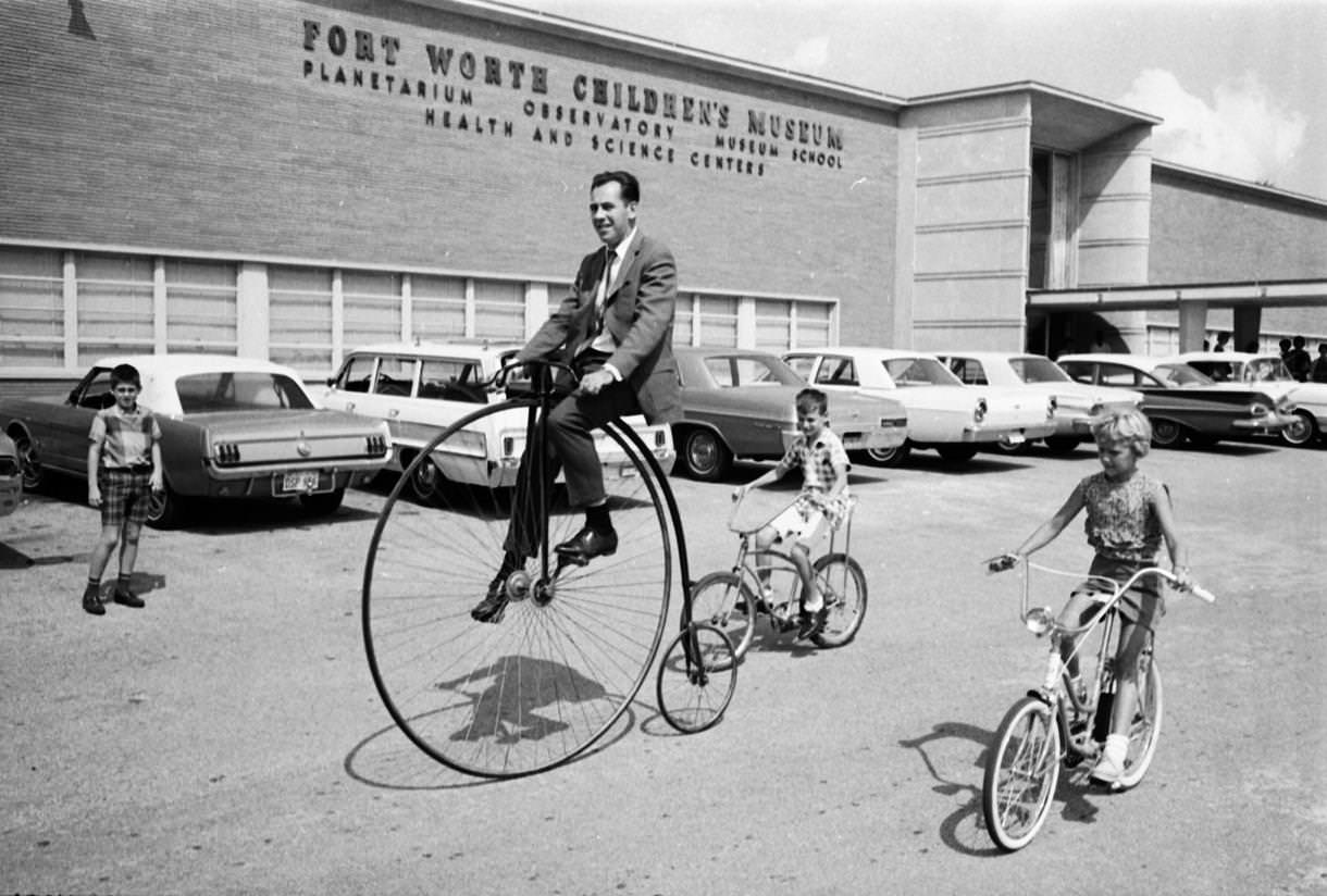 #54 Helmuth Naumer, director of Fort Worth Children’s Museum, rides an old fashioned bicycle, 1967