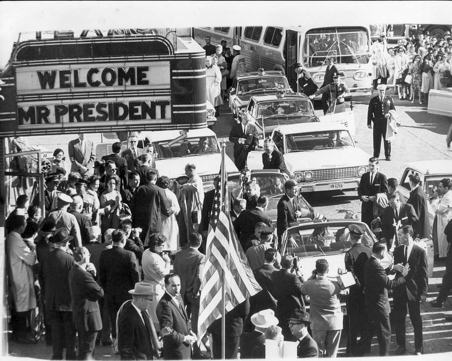 #79 John F. Kennedy standing in convertible car, 1963