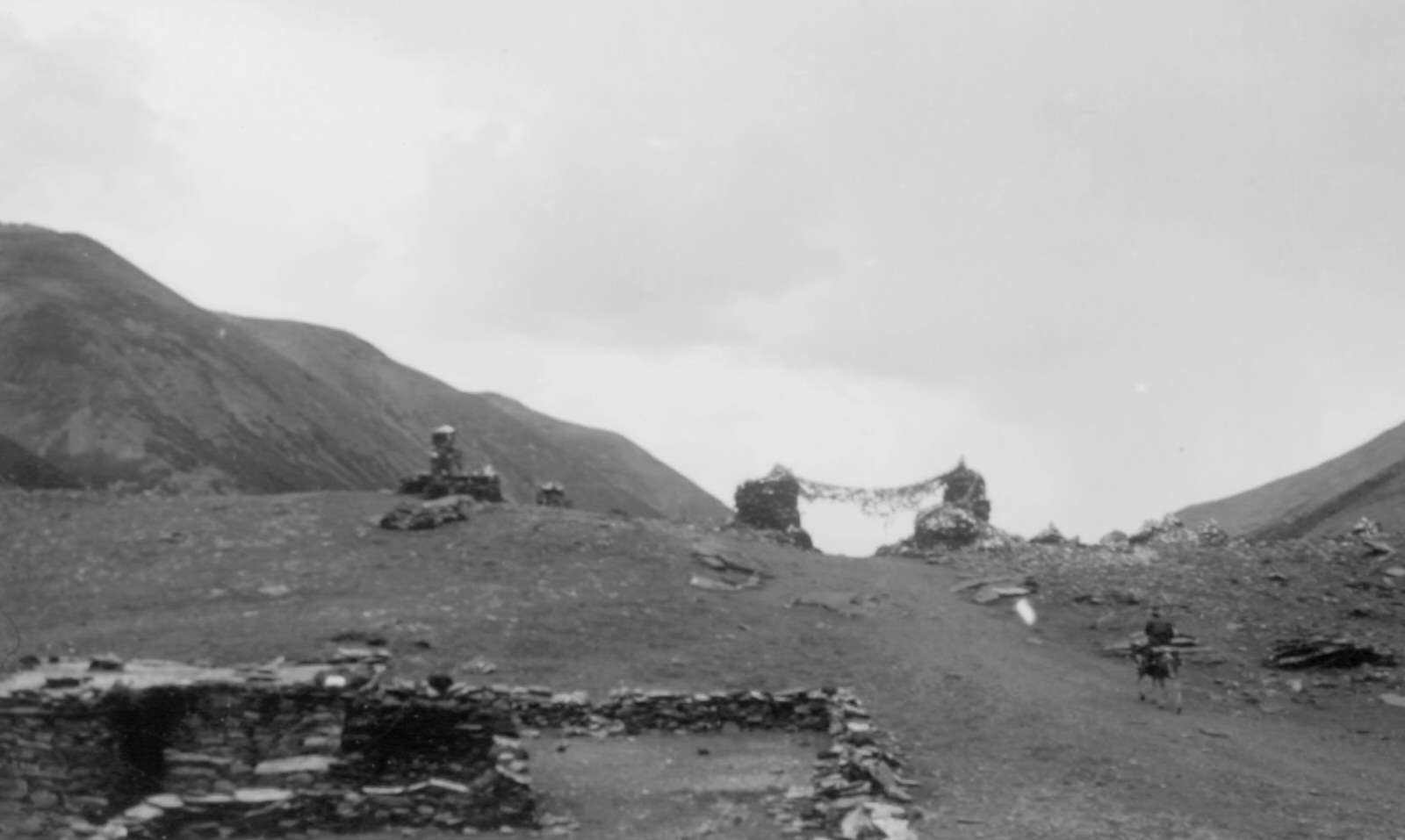 #18 Archway of Stones and Prayer Flags Over the Pass of Kharo-la, 1944. Archway of stones and prayer flags over the 16,400 foot pass of Kharo-la, on road to Lhasa.