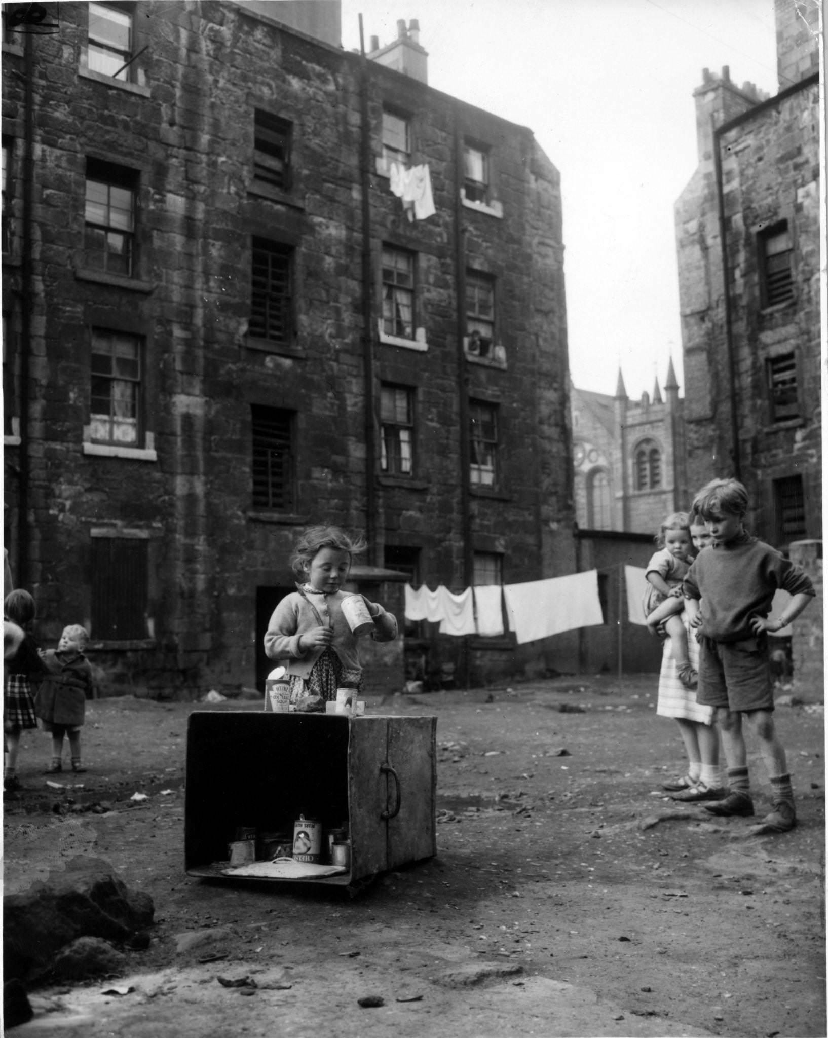 #23 September 1956: Jenny Lamont and her friends play with tin cans in the yard behind tennemants of Florence Street, in the Gorbals area of Glasgow, 1956