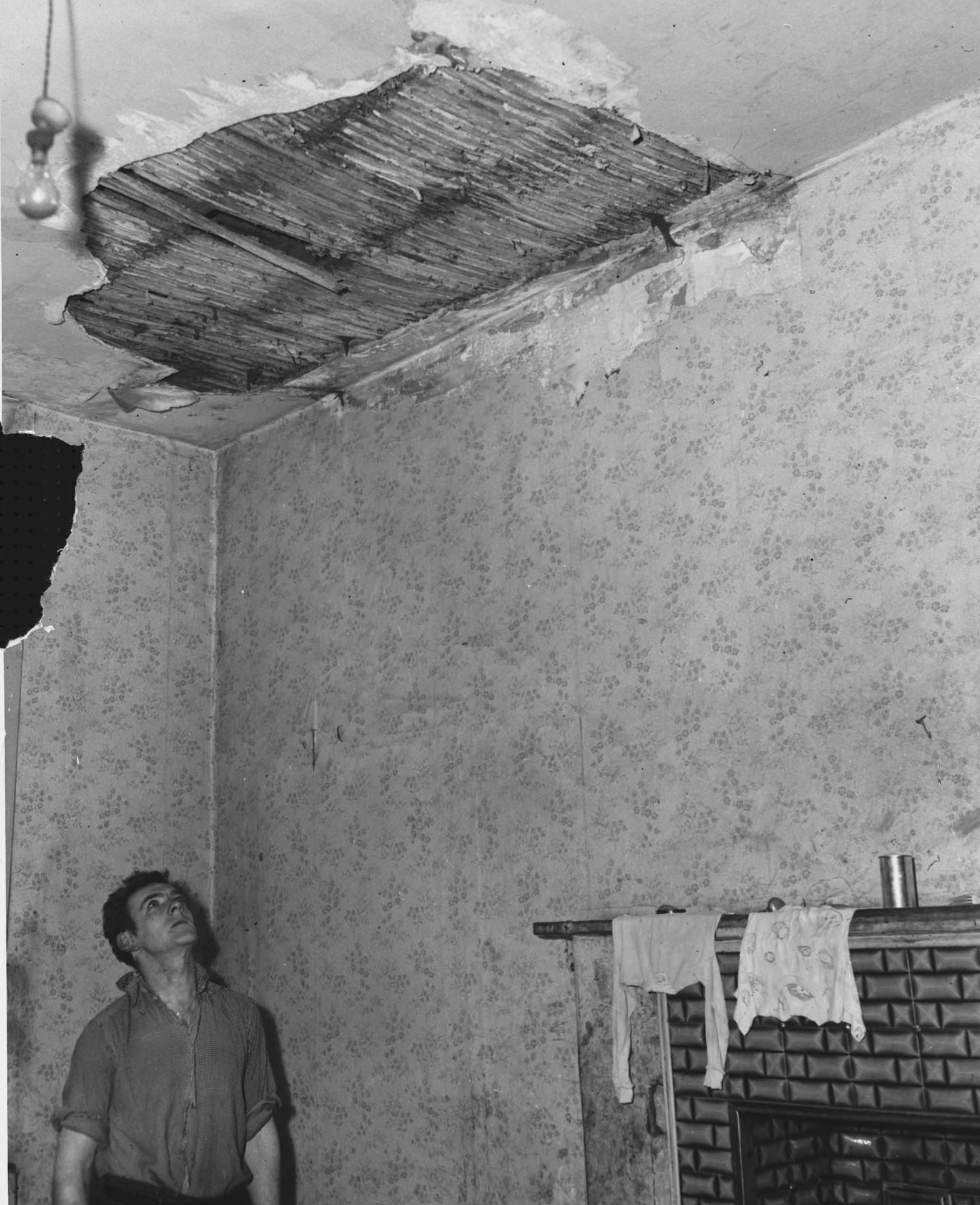#29 Mr. Jackson inspects a hole in the ceiling of his council house in the Gorbals, 1956