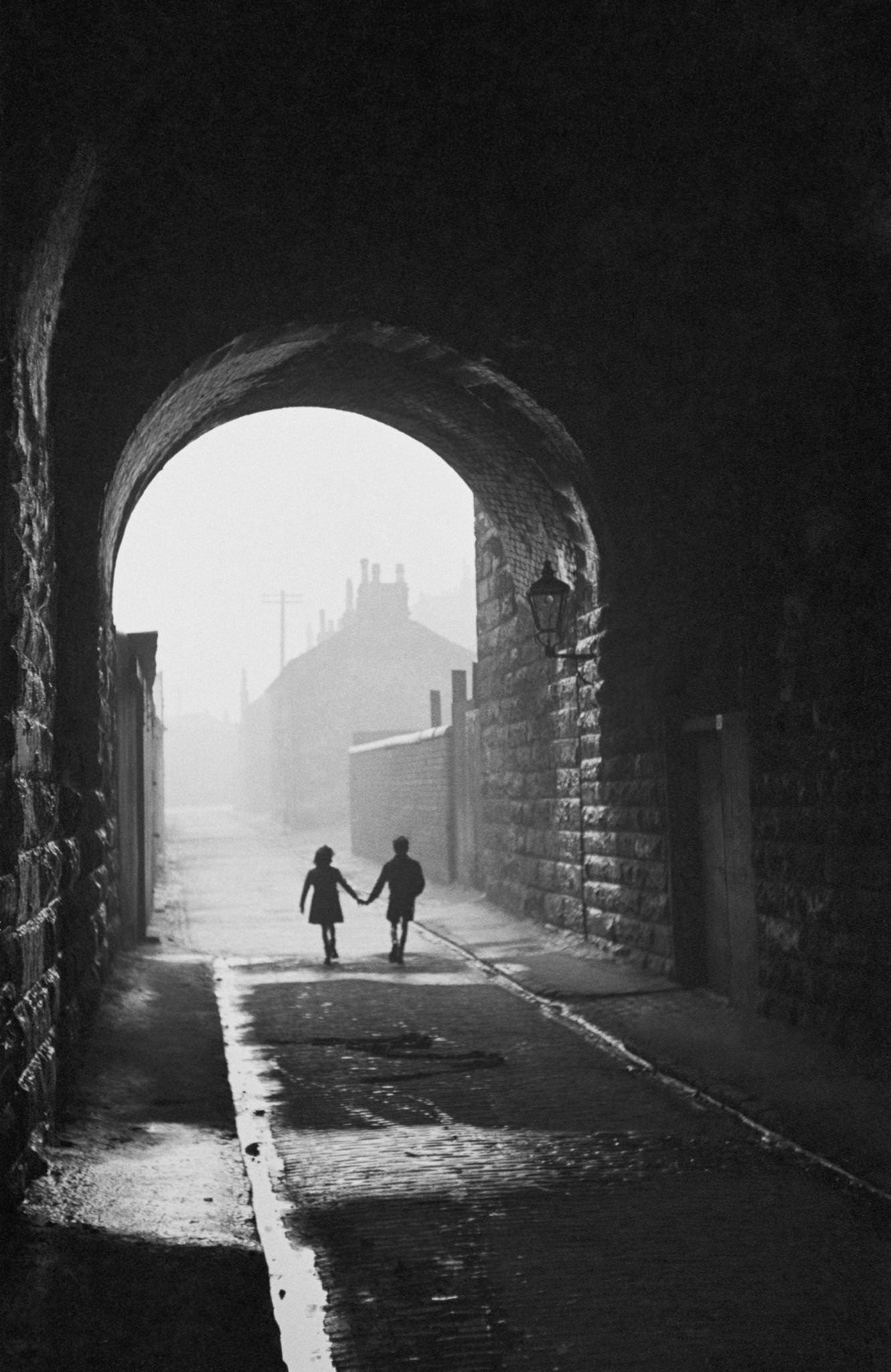 #8 A boy and girl hold hands under an archway in the Gorbals, a slum district of Glasgow, 31st January 1948.