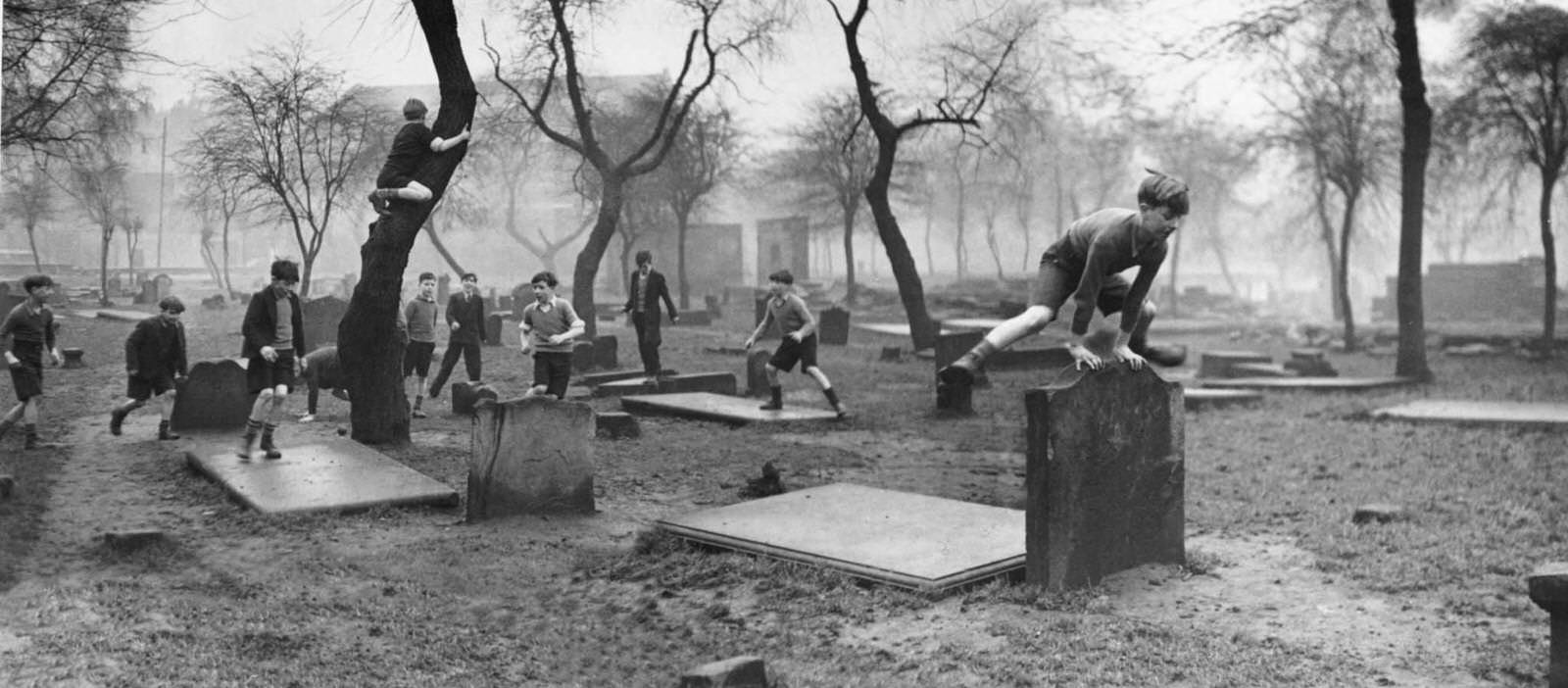 #42 A group of boys from the Gorbals play amongst the gravestones of the Corporation Burial Ground in Rutherglen Road, one of the few areas of greenery in the district, 1948