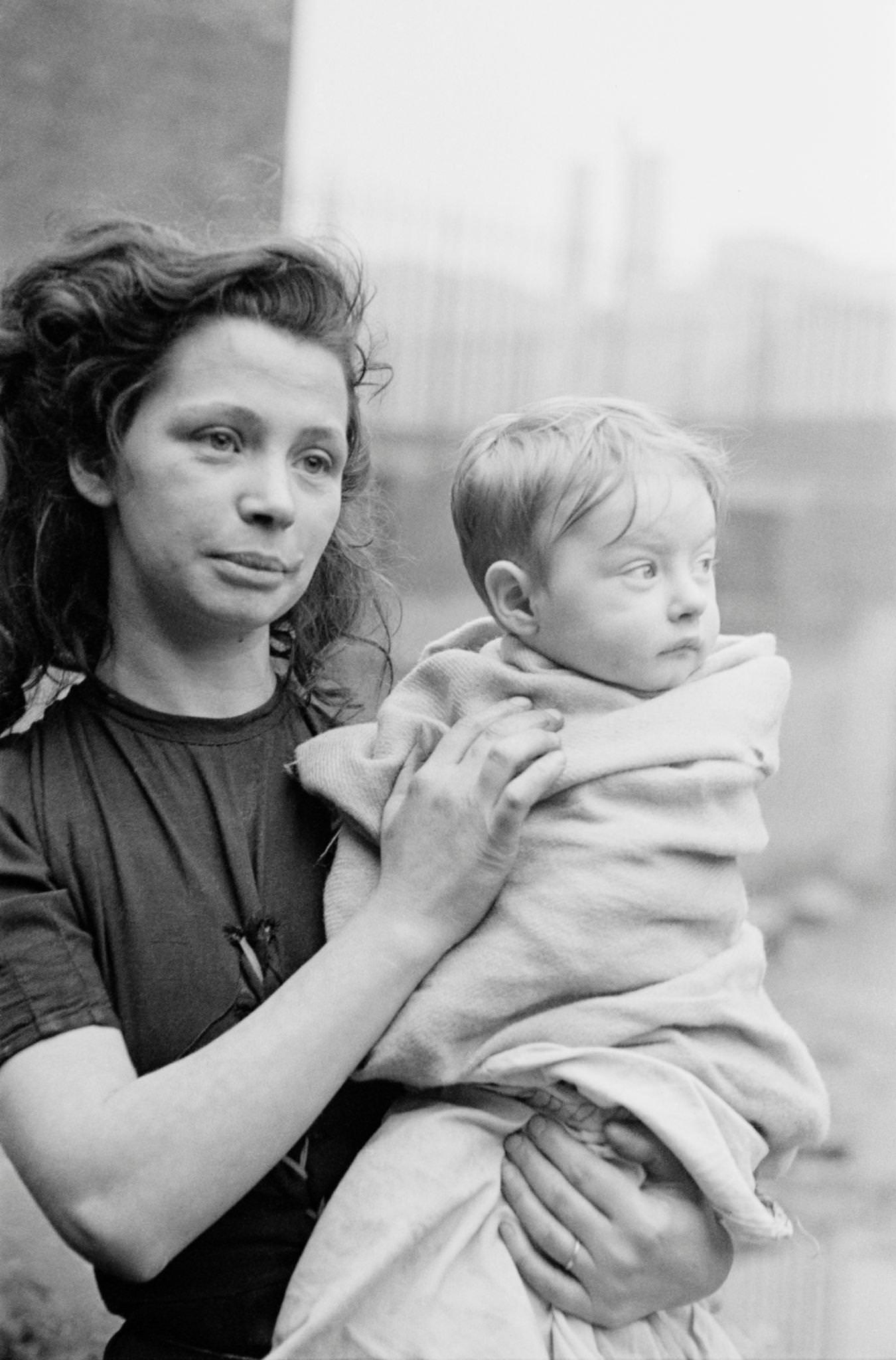 #52 A young woman holding a baby wrapped in a blanket in the Gorbals, a slum district of Glasgow, 1948.