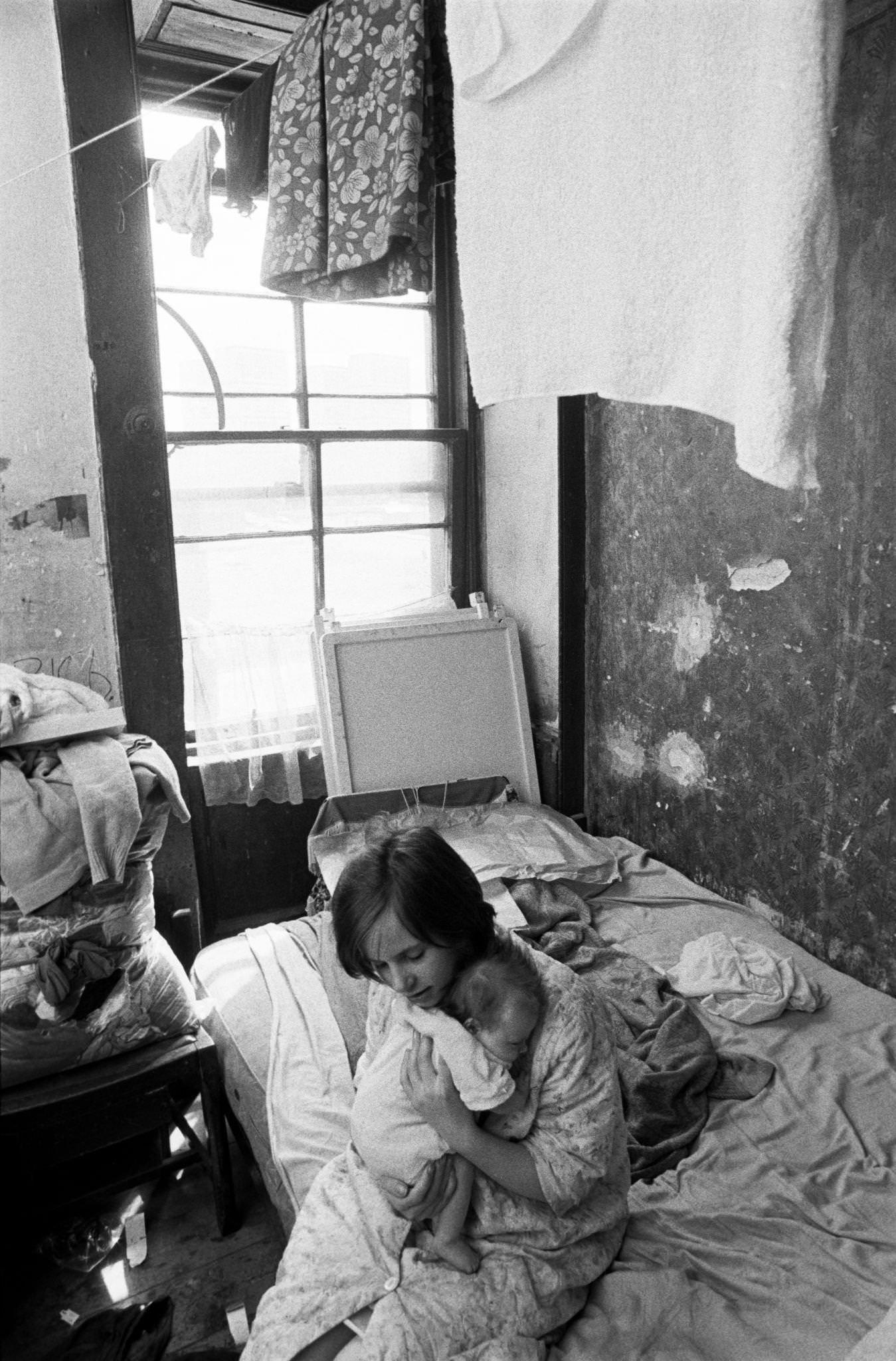 #63 A young girl holding a little baby in her flat in the notorious Gorbals district of Glasgow, 1969.