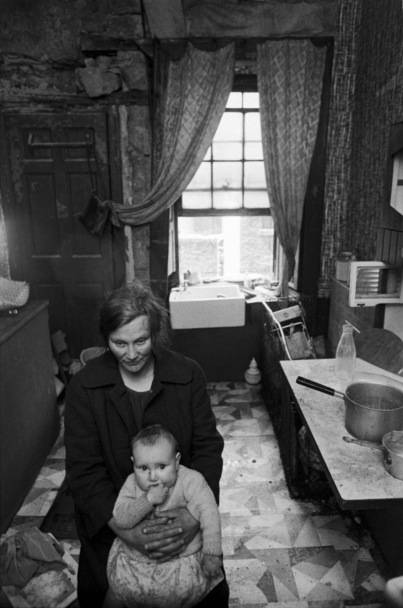 #66 A mother holding her child in the kitchen of her flat in the notorious Gorbals district of Glasgow, 1969.
