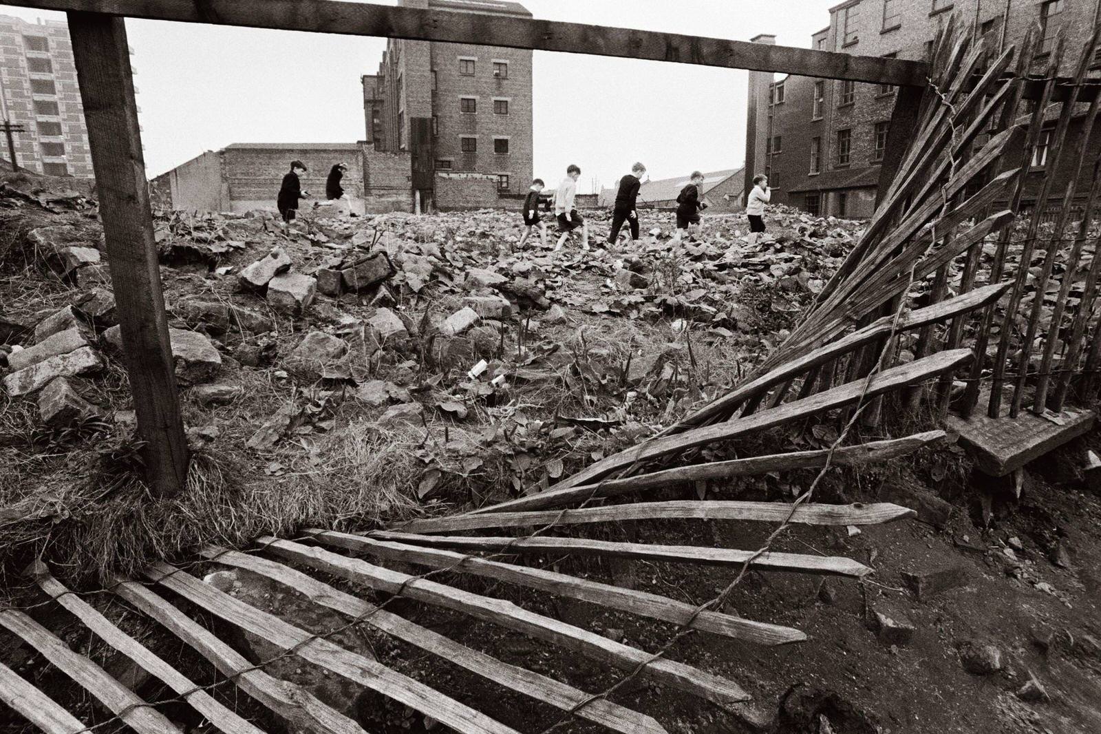 #69 A group of boys pick their way through a wasteland in the Gorbals area of Glasgow, 1968.