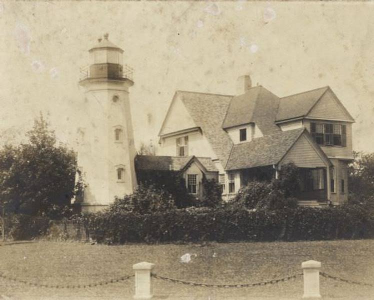 #69 A chain and posts border the yard of the lighthouse, which is attached to a two-story house, 1895