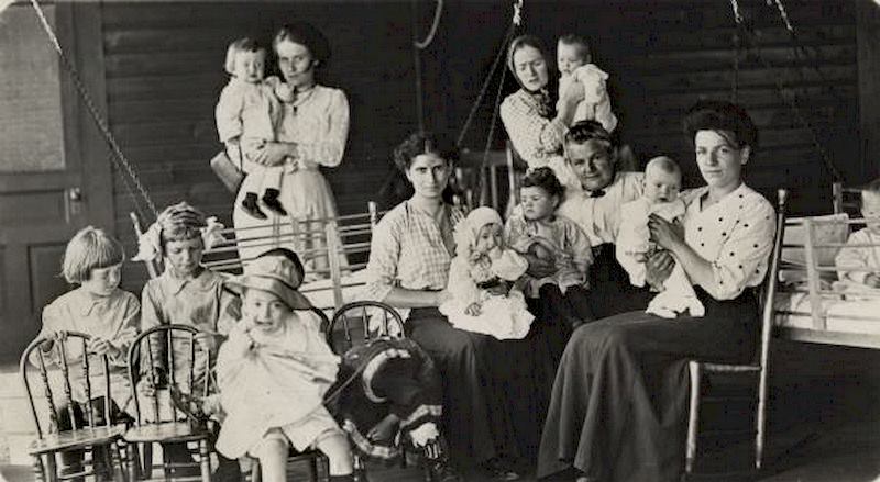 #83 Women of various ages are surrounded by babies and young children, as well as chairs and cribs, 1897