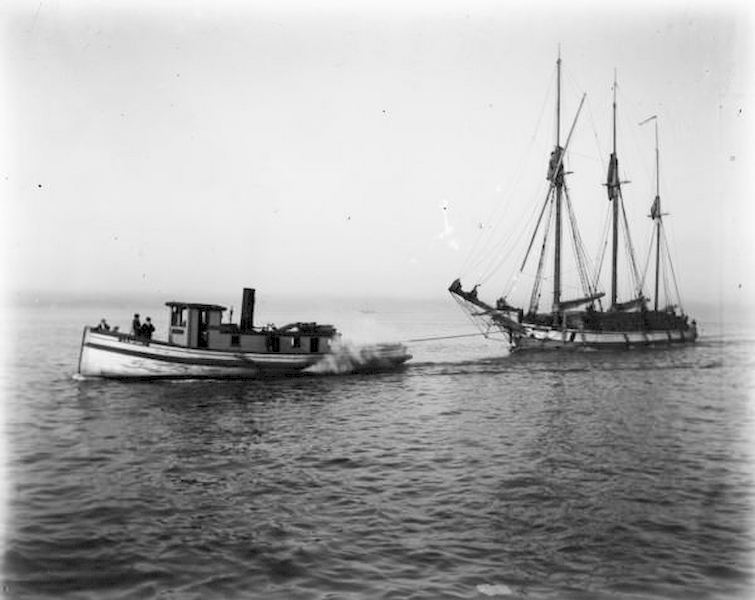 #88 View across water of a tugboat pulling a sailboat towards Milwaukee on Lake Michigan, 1898