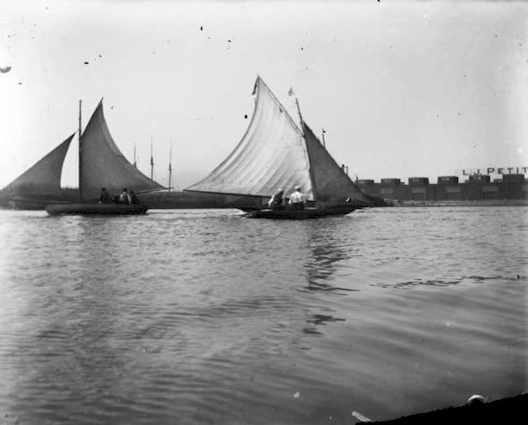 #90 Small sailboats in Milwaukee Harbor with buildings on the far shoreline in the background, 1898