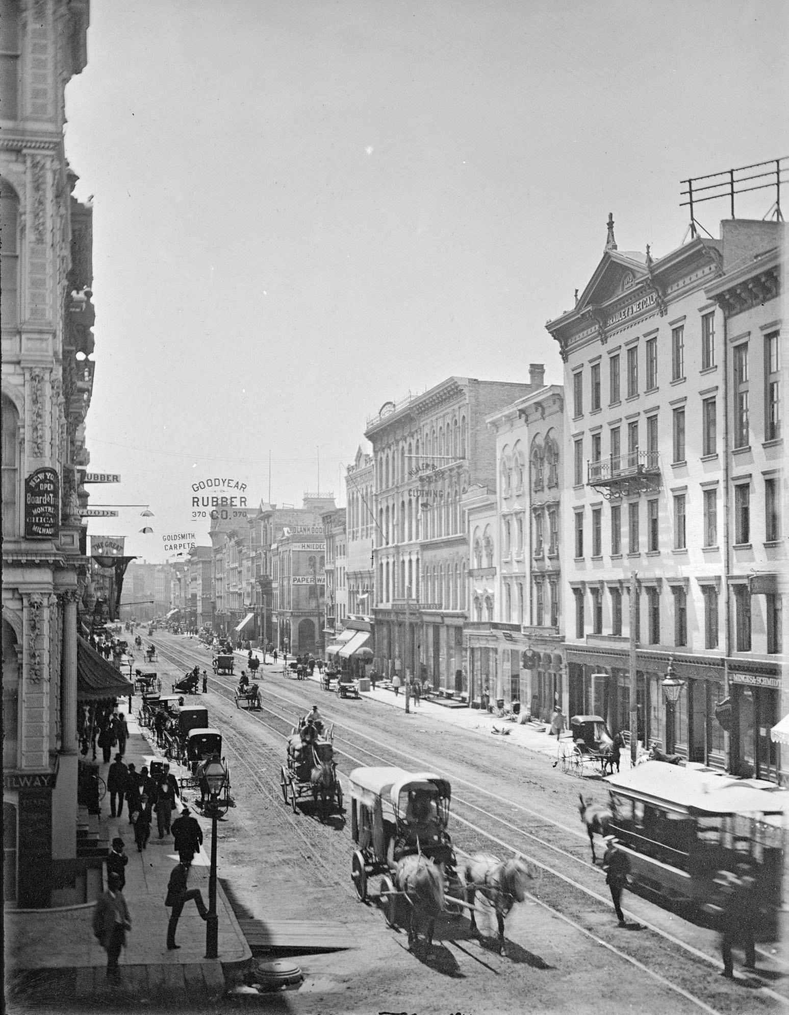 #69 Elevated view down East Water Street from Wisconsin Avenue, with buildings, people, and street traffic including horse-drawn vehicles and a horse-drawn streetcar, Milwaukee, Wisconsin, 1885.