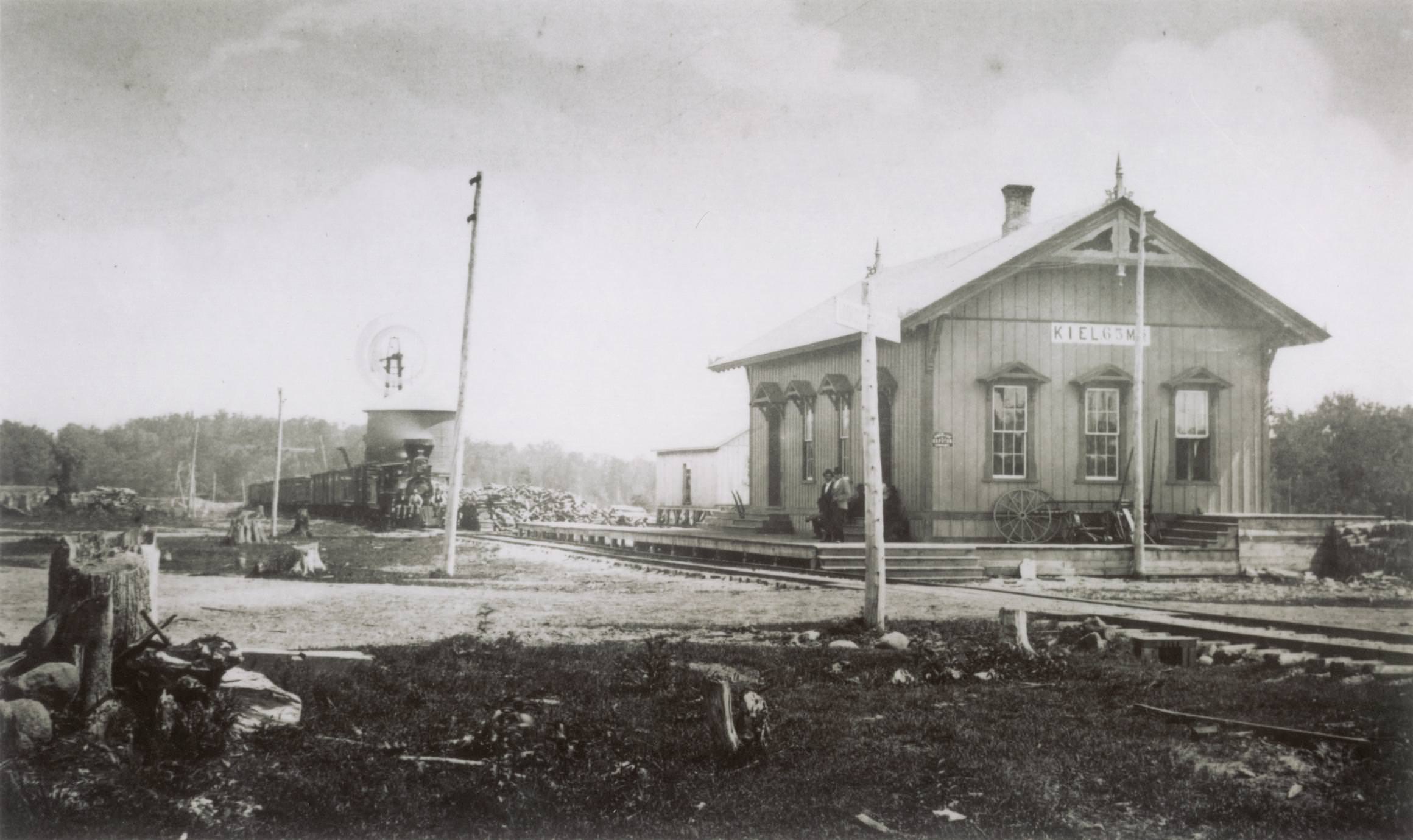 #2 Two men are standing on the platform outside of Kiel’s first Depot, 1870
