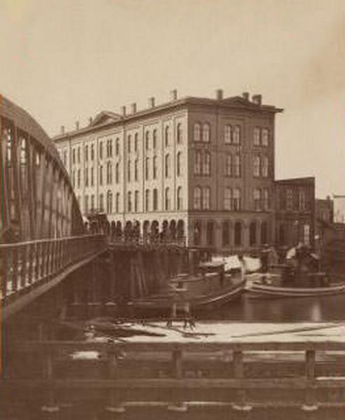 #24 Axtell House building, with a storefront next to it advertising “Clothing Hats Caps Sailors Outfits”., 1869