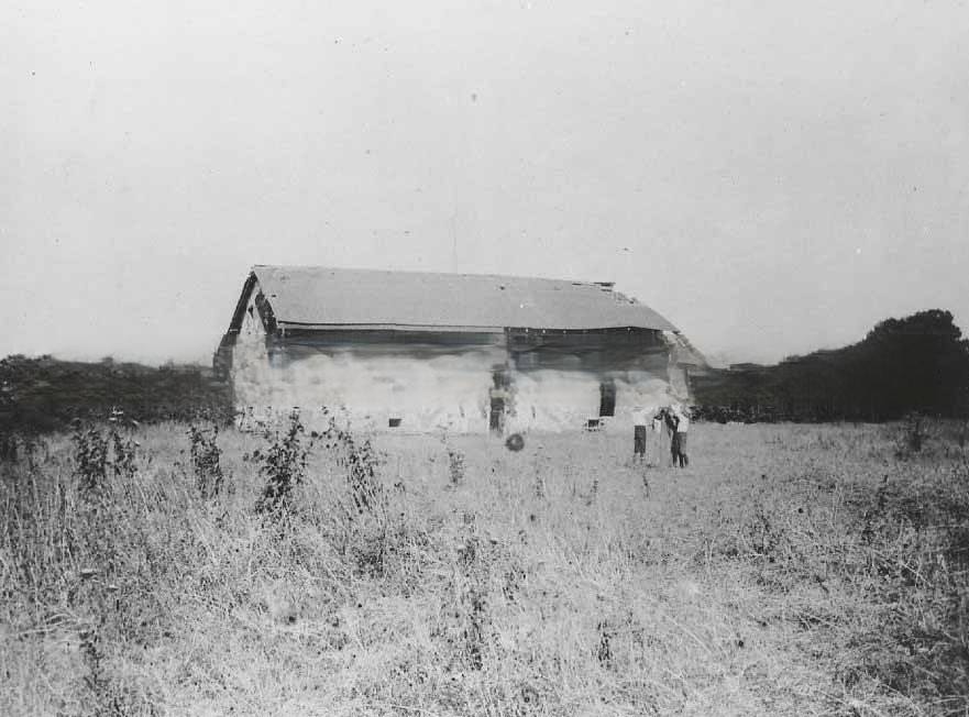 #52 Sutter’s Fort central building before rebuilding. View with a man and two boys standing next to the building, 1889