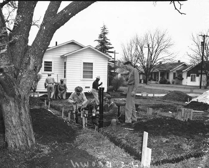#43 Willard Sampson watching installation of plumbing at new house site, 1953