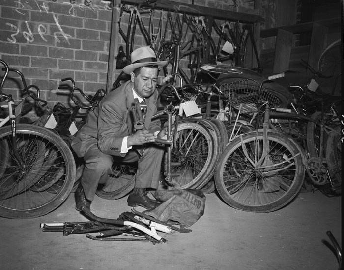 #35 Police Detective Sixto Sepulveda with stolen bicycle parts stored in police headquarters basement, 1950