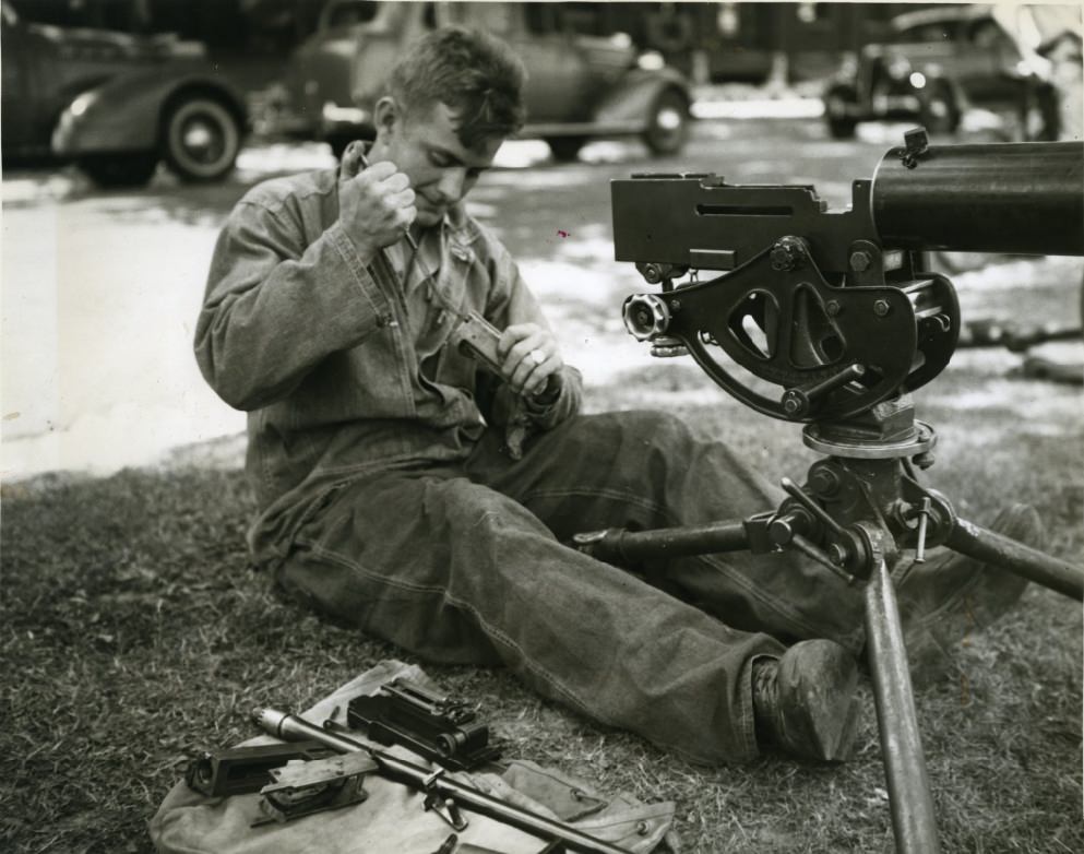 #51 Private Bredemeyer thought he would take this machine gun apart to see what made it “tick.” An apparent case of “spring fever” is handicapping his efforts to get it back together again, 1937