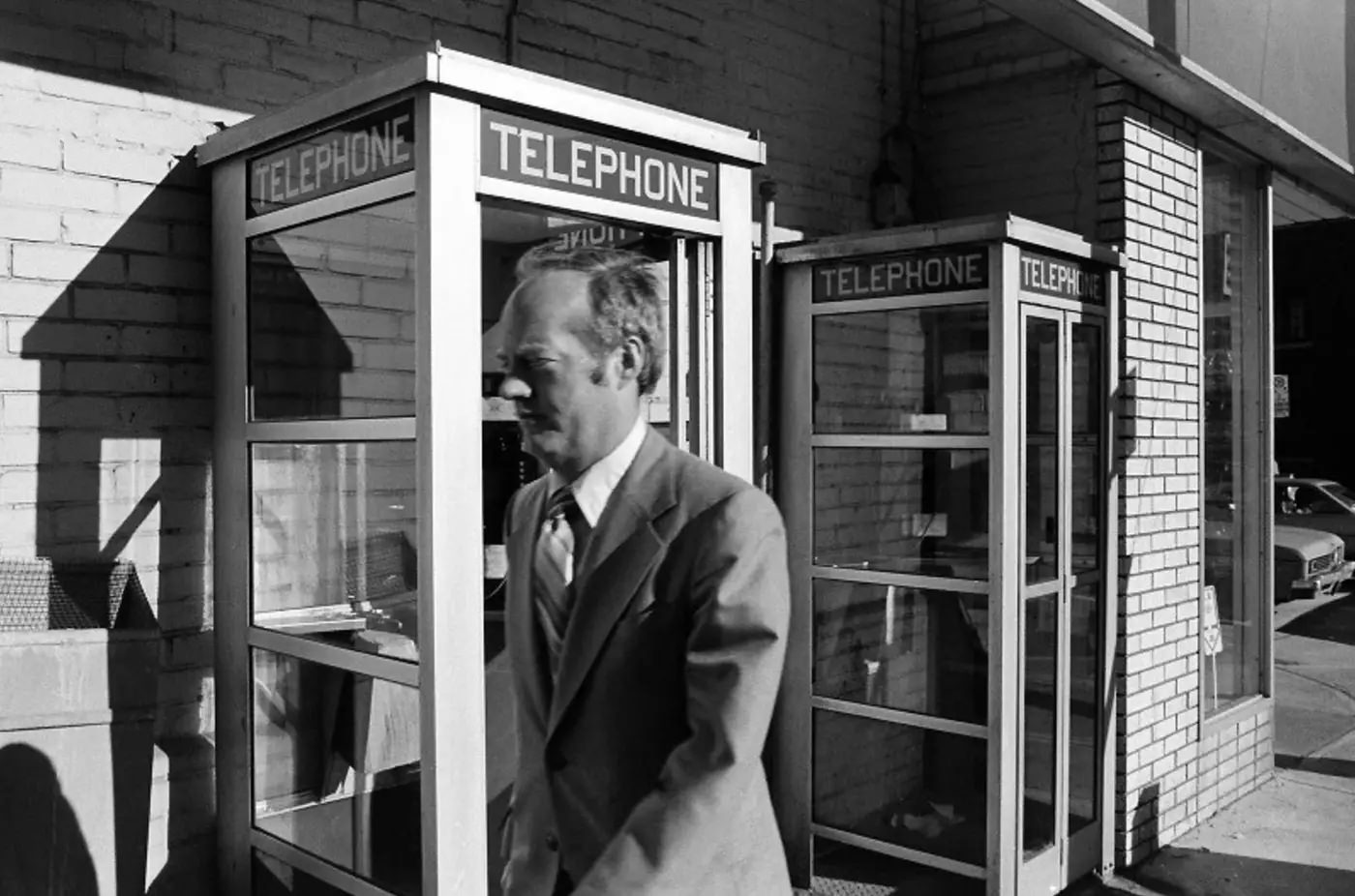 #48 Man walking by phone booths in 1980.