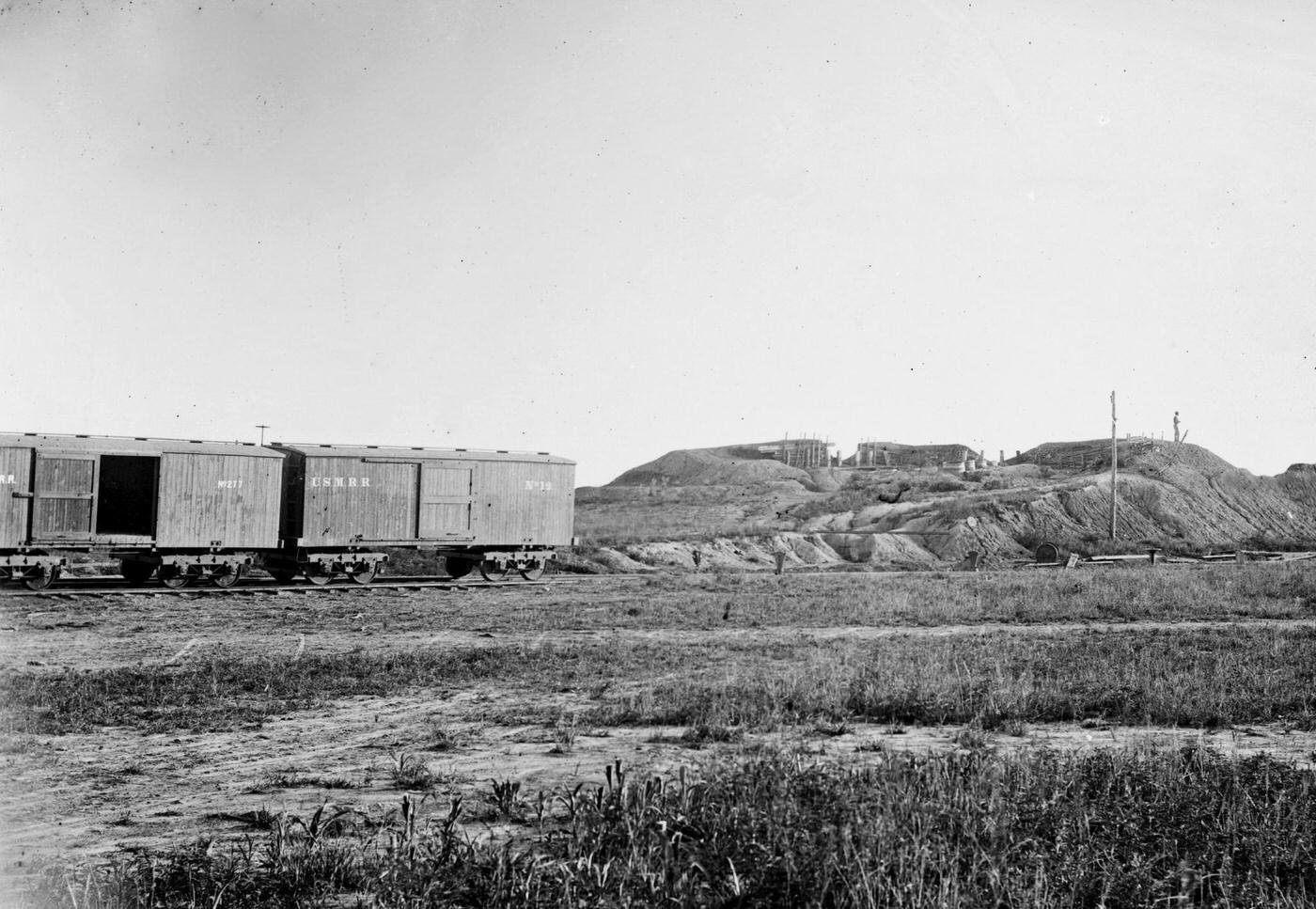 #80 US military railroad boxcars travel along the Orange & Alexandria railroad line, Confederate fortifications are visible on the right, 1862.