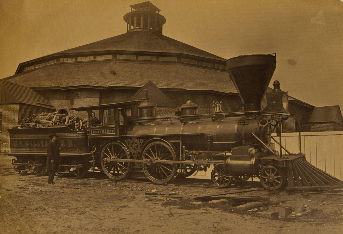 #162 Wood burning locomotive “Gen. Haupt” named for Herman Haupt, chief of Construction and Transportation, in front of the roundhouse at the Alexandria station, 1863