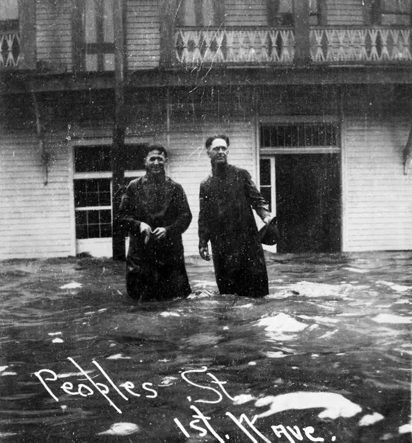 #104 Two men wade onto Peoples Street as water begins to push into the streets as the 1919 hurricane approached.
