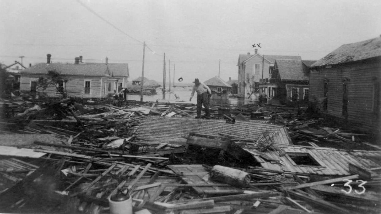 #35 A man standing on a roof that lies on the ground after the hurricane of 1919 in Corpus Christi.