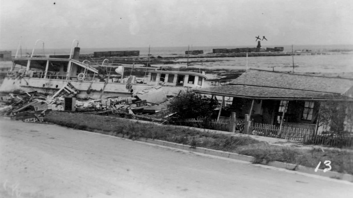 #62 The Japonica wrecked on the shoreline. A small building stands precariously to the right, 1919