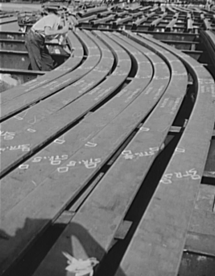 #14 Thousands of workers contribute thousands of skills in the building of ships for Uncle Sam’s growing Navy. This worker is topping punching holes on a ship’s frame, 1941