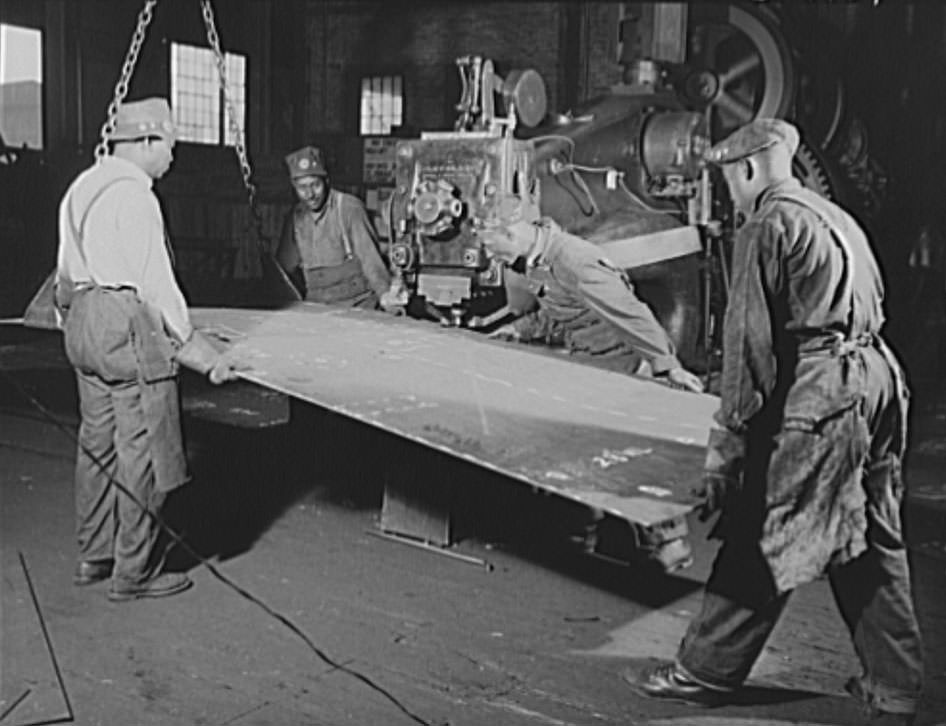 #18 These four workers are guiding a steel plate through a punch press, 1941